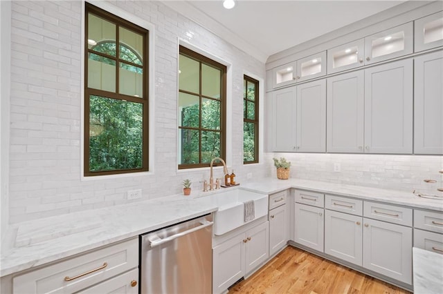 kitchen with dishwasher, plenty of natural light, decorative backsplash, and light wood finished floors