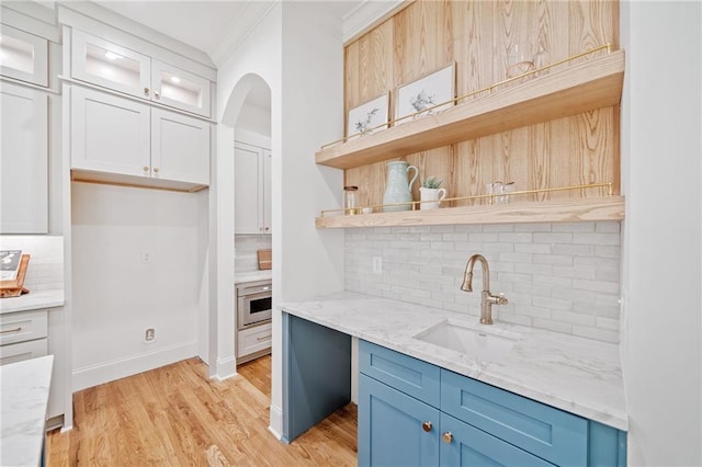 kitchen with a sink, oven, backsplash, open shelves, and blue cabinets