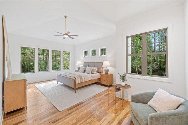 bedroom featuring multiple windows, light wood-style flooring, vaulted ceiling, and a ceiling fan