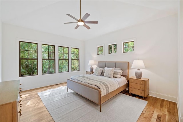 bedroom with multiple windows, light wood-style flooring, baseboards, lofted ceiling, and ceiling fan