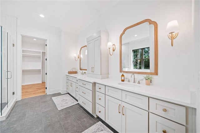 full bathroom with double vanity, a stall shower, a spacious closet, crown molding, and recessed lighting