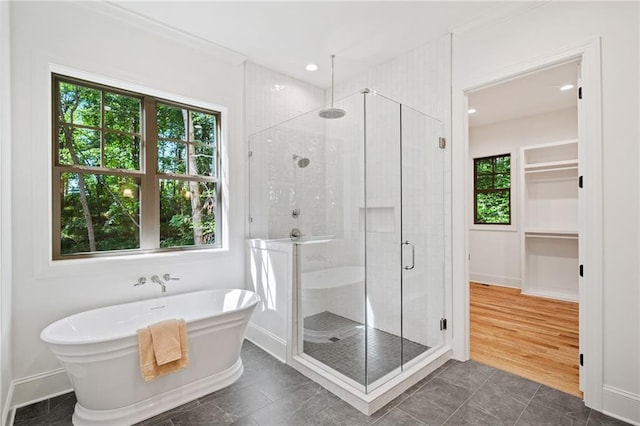 bathroom featuring a stall shower, a soaking tub, baseboards, and recessed lighting
