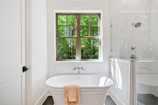 full bathroom with a tile shower, a soaking tub, and baseboards
