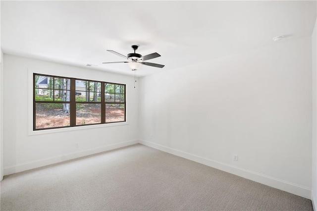 unfurnished room with baseboards, ceiling fan, and light colored carpet