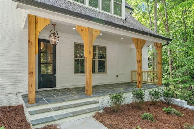 entrance to property featuring a porch and brick siding