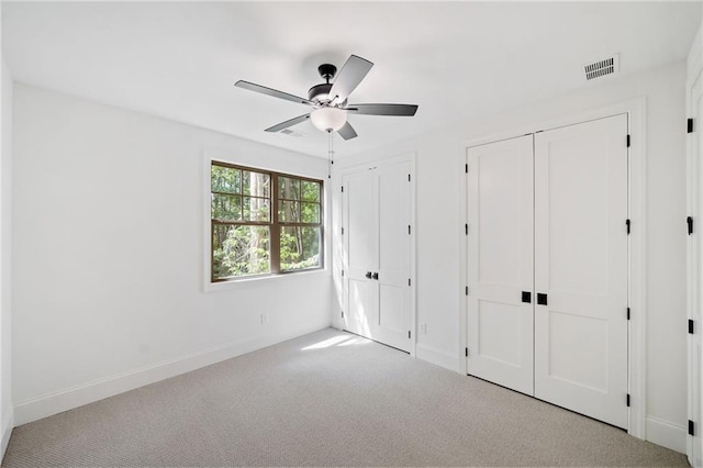 unfurnished bedroom with two closets, carpet, baseboards, and a ceiling fan