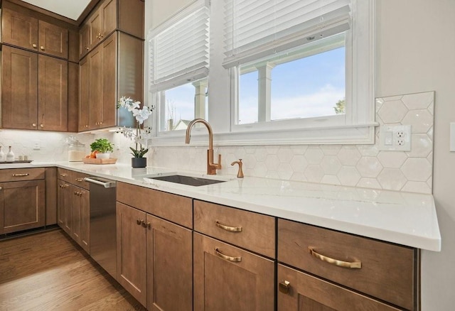 kitchen featuring a sink, stainless steel dishwasher, decorative backsplash, and light countertops