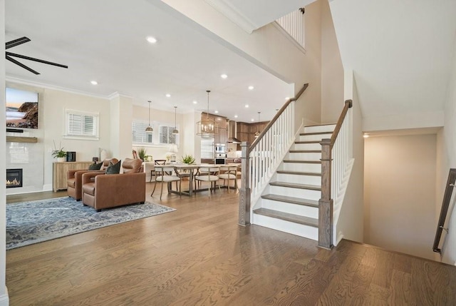 living area with wood finished floors, stairway, a large fireplace, a ceiling fan, and recessed lighting