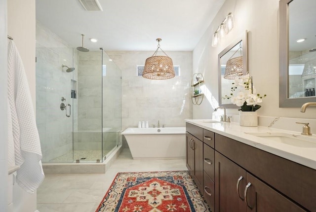 bathroom featuring a stall shower, a soaking tub, a sink, and visible vents