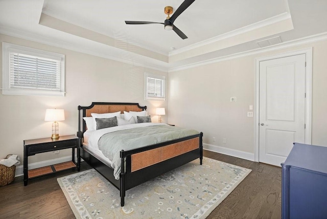 bedroom with a raised ceiling, dark wood-style flooring, multiple windows, crown molding, and baseboards
