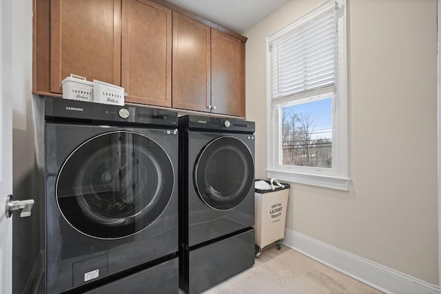 clothes washing area featuring washing machine and dryer, cabinet space, baseboards, and light tile patterned flooring