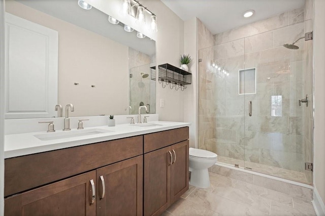 full bath with toilet, a shower stall, double vanity, and recessed lighting