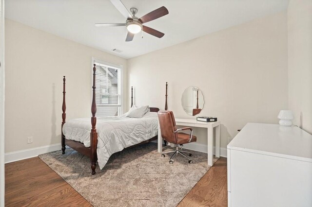 bedroom with ceiling fan, wood finished floors, visible vents, and baseboards