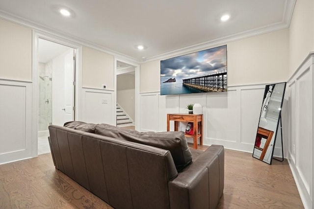 living room with a decorative wall, wood finished floors, stairway, ornamental molding, and a wainscoted wall