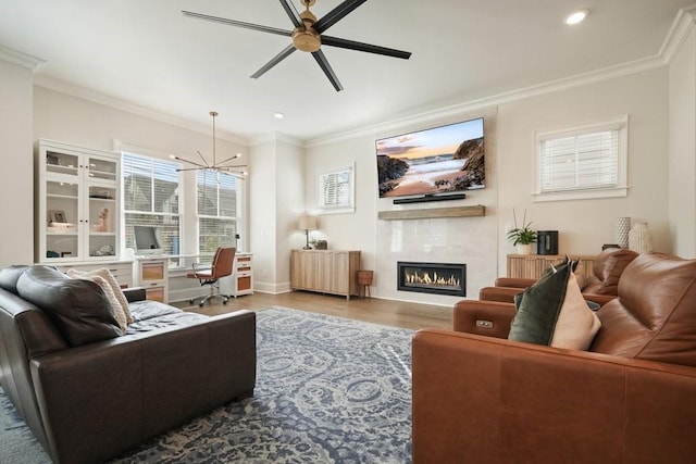 living room featuring a glass covered fireplace, crown molding, and wood finished floors