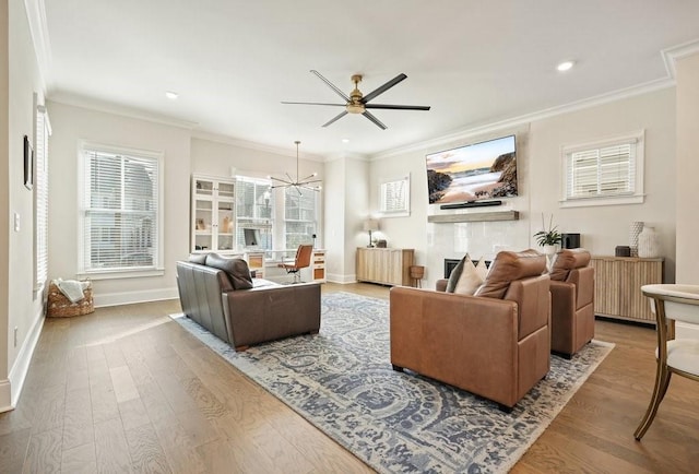 living room with wood finished floors, a ceiling fan, ornamental molding, a chandelier, and recessed lighting