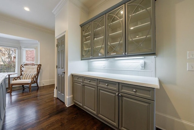 bar with dark wood-style flooring, crown molding, recessed lighting, backsplash, and baseboards