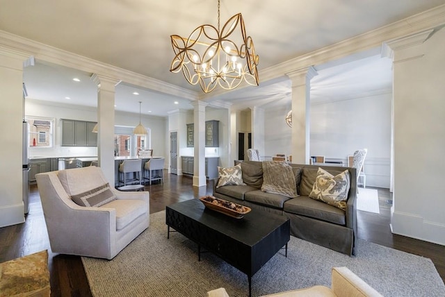 living room with dark wood-style flooring, crown molding, ornate columns, and an inviting chandelier