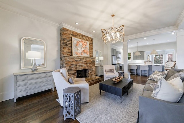 living room featuring a chandelier, dark wood-style flooring, ornamental molding, and a stone fireplace