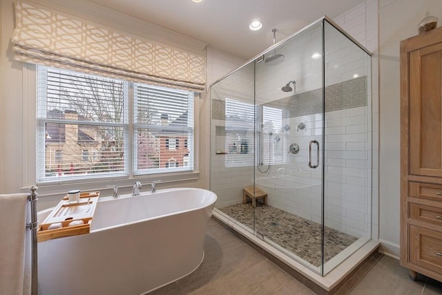 bathroom with recessed lighting, a stall shower, a soaking tub, and tile patterned floors