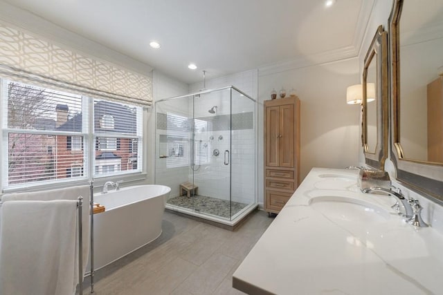 bathroom featuring a freestanding tub, a shower stall, ornamental molding, and a sink