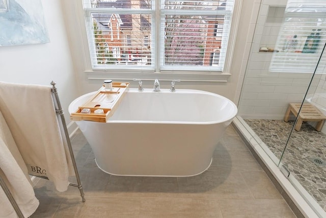 bathroom with a soaking tub, a shower stall, baseboards, and tile patterned flooring