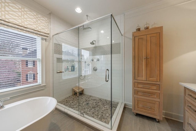 bathroom with a stall shower, a soaking tub, vanity, and baseboards