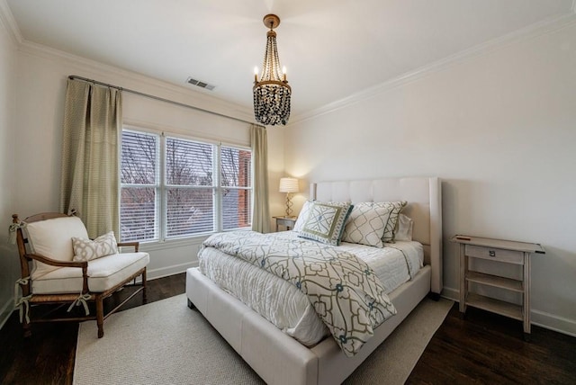 bedroom with wood finished floors, visible vents, baseboards, ornamental molding, and an inviting chandelier