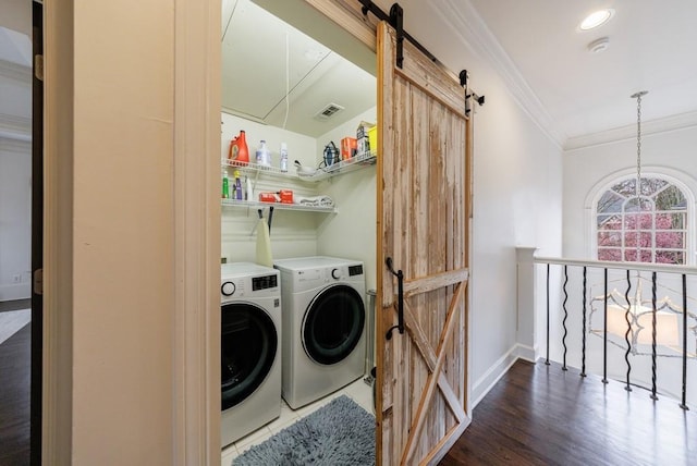 laundry area with a barn door, laundry area, wood finished floors, washing machine and clothes dryer, and crown molding