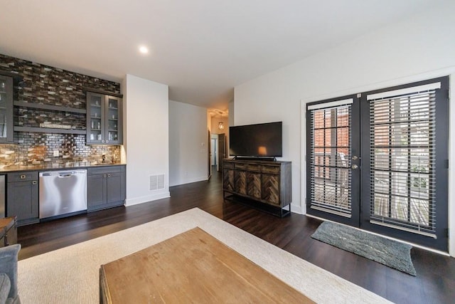 living area featuring a dry bar, baseboards, visible vents, dark wood finished floors, and french doors