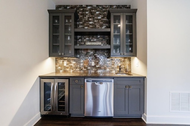 bar with beverage cooler, a sink, visible vents, stainless steel dishwasher, and indoor wet bar