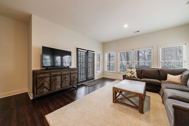 living room featuring dark wood-type flooring, a wealth of natural light, visible vents, and baseboards