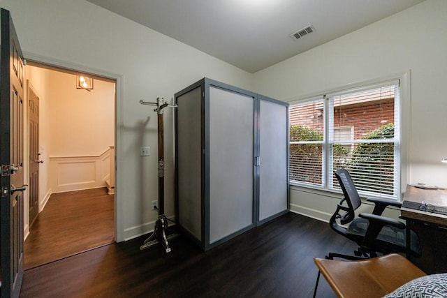 office area with dark wood-style floors, baseboards, visible vents, and a decorative wall