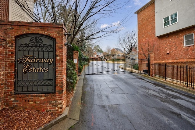 view of road with a gate, a gated entry, and curbs