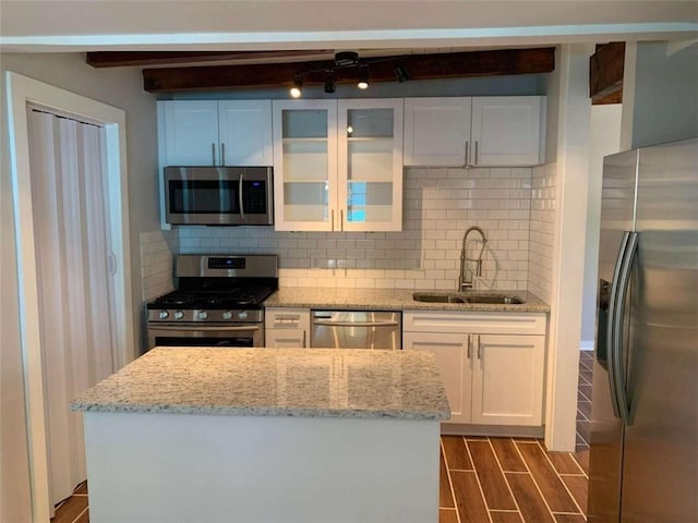 kitchen with appliances with stainless steel finishes, dark hardwood / wood-style flooring, light stone countertops, sink, and white cabinets