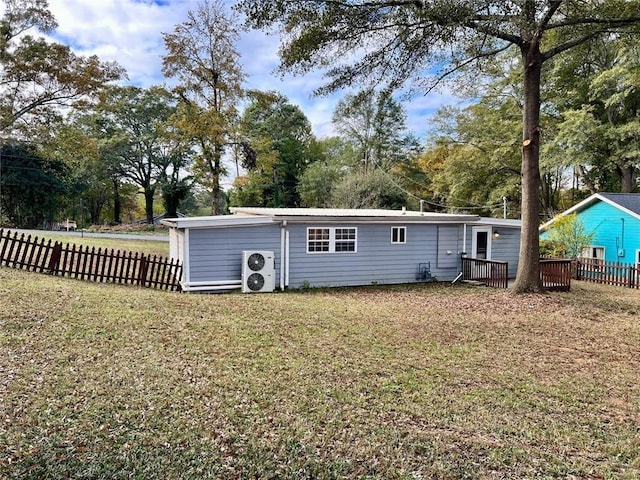 rear view of property featuring a lawn and ac unit