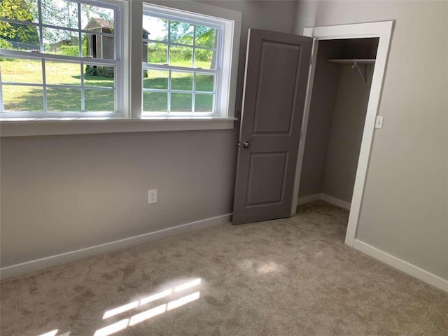 unfurnished bedroom with light colored carpet and a closet