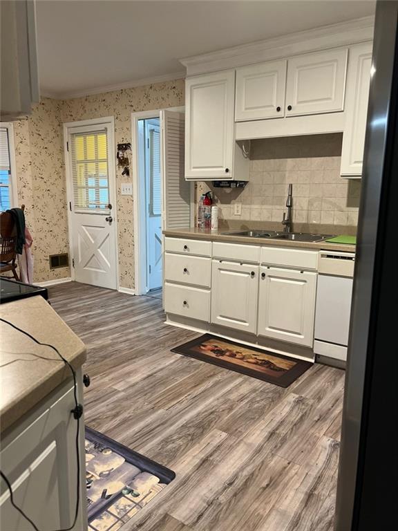 1017 Clifton Dr, Macon, GA 31204 - kitchen featuring a sink, dark wood-type flooring, wallpapered walls, white cabinets, and ornamental molding