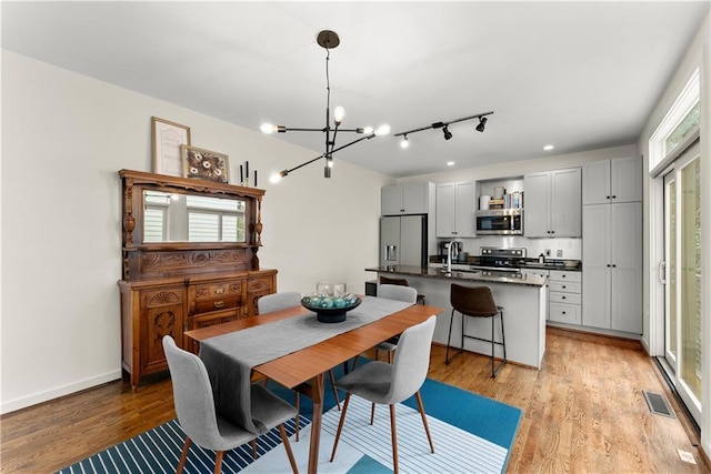 1382 Stirling Cir NW, Atlanta, GA 30318 - dining space featuring baseboards, visible vents, an inviting chandelier, and light wood-style floors