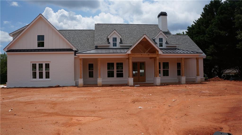 1300 Grapevine Trl, Monroe, GA 30656 - modern farmhouse style home featuring a standing seam roof, a shingled roof, covered porch, and metal roof