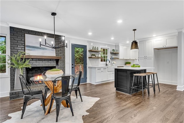 kitchen featuring pendant lighting, light wood-type flooring, white cabinetry, a kitchen breakfast bar, and ornamental molding