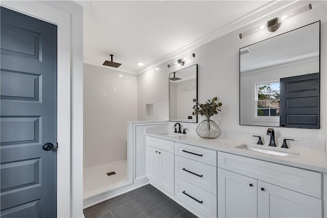 bathroom with a tile shower, vanity, and tile patterned floors