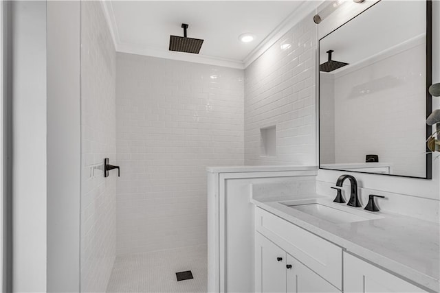 bathroom with a tile shower, vanity, and ornamental molding