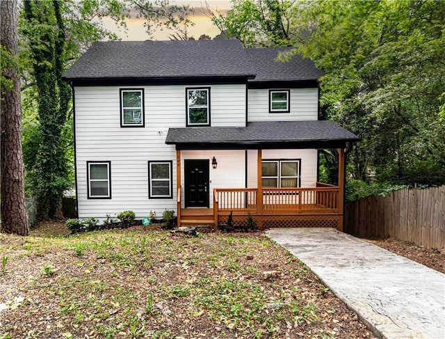 view of front of house with a porch, roof with shingles, and fence