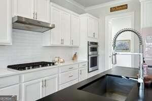 247 Widener Way, Peachtree City, GA 30269 - kitchen featuring stainless steel dishwasher, a ceiling fan, healthy amount of natural light, a fireplace, and crown molding