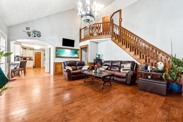 living room with a notable chandelier, wood-type flooring, and high vaulted ceiling