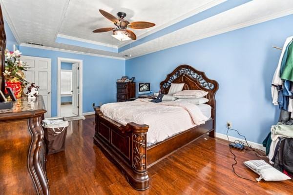 bedroom featuring crown molding, dark hardwood / wood-style floors, ceiling fan, and a tray ceiling