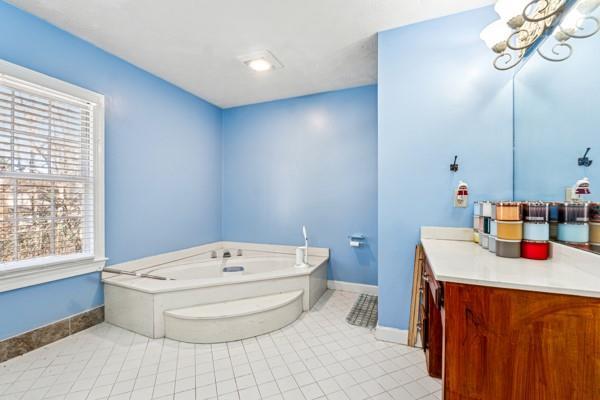 bathroom featuring vanity, a bath, tile patterned floors, and a chandelier