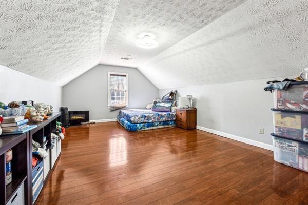 bedroom featuring lofted ceiling, hardwood / wood-style floors, and a textured ceiling