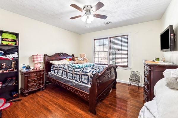 bedroom with ceiling fan, dark hardwood / wood-style floors, and a textured ceiling